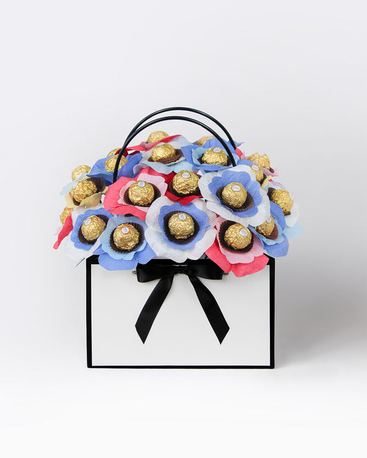 High Tea-inspired chocolate bloom box with chocolate-centred flowers in denim blue, cornflower blue, blush pink, rose red, and creamy white – handmade, whimsical, and perfect as a personalised gift bouquet.